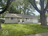 Charming single-story home with lush green lawn, complemented by mature trees at 1306 Woodbine Dr, Anderson, IN 46011