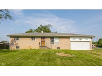 Ranch-style home with light brick, a front lawn, and an attached garage on a sunny day at 1310 S Catherwood Ave, Indianapolis, IN 46203