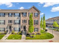 Charming brick and siding townhouse with a well-manicured lawn and inviting front entrance on a beautiful, sunny day at 3546 Brampton Ln, Westfield, IN 46074
