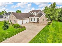 Beautiful brick home featuring an attached three-car garage and a well-manicured lawn with colorful flower beds at 720 Willow Pointe North Dr, Plainfield, IN 46168