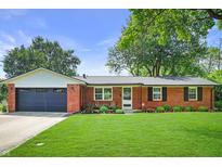 Charming brick home with well-manicured lawn, black shutters, an attached garage, and beautiful landscaping at 7234 Fairwood Dr, Indianapolis, IN 46256