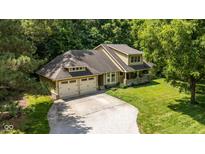 Inviting yellow two-story home boasts an attached two-car garage and a charming covered front porch with stone supports at 9722 N Gasburg Rd, Mooresville, IN 46158