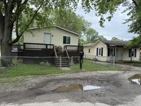 View of a two yellow houses with a fenced yard and an old driveway at 3301 S Lockburn St, Indianapolis, IN 46221