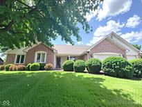 Beautifully landscaped front yard with lush green grass, mature trees, and a classic brick home at 3975 Keyway Dr, Greenwood, IN 46143