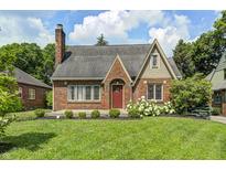 Charming brick home featuring a well-manicured lawn, flowering bushes, and a classic red door at 5430 N Kenwood Ave, Indianapolis, IN 46208