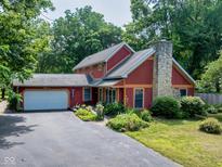 Charming two-story home with a stone chimney, attached garage, and professionally landscaped yard at 5631 Shelby St, Indianapolis, IN 46227