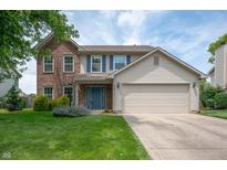 Charming two-story home featuring a well-manicured lawn, blue door, and a mix of brick and siding at 6562 Quail Run, Fishers, IN 46038