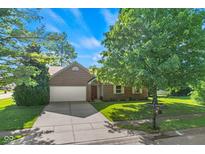Charming brick home with an attached two-car garage, long driveway, lush lawn, and mature trees at 7239 N Orchard Dr, Indianapolis, IN 46236