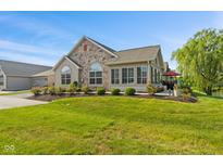 Inviting home featuring a stone front, arched windows, green lawn and outdoor patio at 7850 King Post Dr, Indianapolis, IN 46237