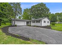 Charming white brick ranch-style home with attached garage and a large, resurfaced driveway and manicured landscaping at 8105 Allisonville Rd, Indianapolis, IN 46250