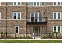 Charming brick townhome featuring a balcony, stylish windows, and a landscaped front yard with a welcoming entrance at 1461 Whistle Way, Westfield, IN 46074