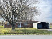 Charming single-story brick home featuring mature trees, a covered entry, and a detached carport at 9842 N State Road 9, Pendleton, IN 46064