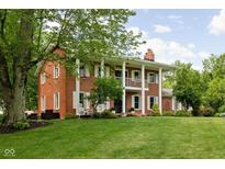 Stately brick home with white columns and shutters, surrounded by lush greenery and mature trees at 10198 N State Road 75, North Salem, IN 46165