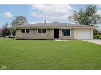 Charming stone-clad home with a well-maintained lawn and attached garage at 10434 N Delaware St, Carmel, IN 46280