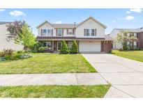 Charming two-story home featuring a well-manicured lawn, brick accents, and an attached two-car garage at 10611 Armstead Ave, Indianapolis, IN 46234