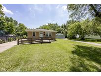 Cozy single-story home with a brick facade, a ramp, a well-maintained lawn and a detached garage at 1217 S Ewing St, Indianapolis, IN 46203