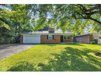 Charming brick home featuring an attached garage, freshly cut lawn, and mature trees providing ample shade at 1231 N Graham Ave, Indianapolis, IN 46219
