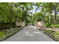 Long driveway to gated entrance with stone pillars and manicured flowerbeds at 1616 W 116Th St, Carmel, IN 46032