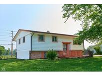 Split-level home with white siding, orange trim, brick accents and a small front porch at 2606 Shakespeare Dr, Southport, IN 46227