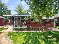 Charming brick bungalow featuring a covered porch and well-maintained front lawn at 319 S Webster Ave, Indianapolis, IN 46219