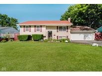 Charming split-level home featuring a spacious lawn, manicured bushes, and a red roof that adds character to the residence at 4020 Eisenhower Dr, Indianapolis, IN 46254