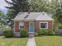 Charming brick home features a cozy front porch, vibrant blue door, and manicured landscaping at 4523 Kingsley Dr, Indianapolis, IN 46205