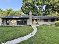 Charming single-story home with manicured lawn, yellow front door, and brick accents at 6430 N Rural St, Indianapolis, IN 46220