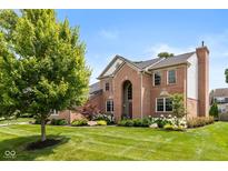 Two-story brick home featuring an arched entryway, manicured lawn, and mature trees providing curb appeal at 11995 Gray Eagle Dr, Fishers, IN 46037