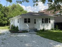 Charming single-story home with gravel driveway and a cozy front porch, perfect for relaxing outdoors at 1605 S Leland Ave, Indianapolis, IN 46203