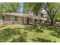 Elegant home featuring stone detailing, lush green lawn, and mature trees adding curb appeal at 1930 Bechtel Rd, Indianapolis, IN 46260