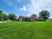 Charming brick home with a well-maintained lawn and mature trees under a blue sky at 3415 Winchester Dr, Indianapolis, IN 46227