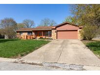 Charming single-story home with an attached garage, well-kept lawn, and a inviting orange front door at 40 S Restin Rd, Greenwood, IN 46142