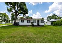 Charming home featuring a well-manicured lawn and beautiful, mature tree offering shade at 4639 Terrace Ave, Indianapolis, IN 46203