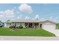 Charming single-story home with a manicured lawn and a cozy front porch decorated with patriotic decor at 6550 Reed Rd, Pittsboro, IN 46167