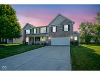 Charming two-story home with well-manicured lawn and inviting front porch at dusk at 12847 Arvada Pl, Fishers, IN 46038
