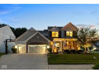 Charming two-story home with a three-car garage, manicured lawn, and inviting front porch at twilight at 12998 Silbury Hill Way, Fishers, IN 46037