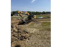 Construction site with a CAT excavator digging a trench next to a pond in preparation for new home construction at 1424 Chatham Ridge Ct, Westfield, IN 46074