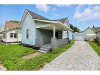 Charming home with a covered front porch, light blue siding and gravel driveway at 410 Montgomery St, Shelbyville, IN 46176