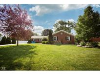 Charming brick home featuring a well-manicured lawn, mature trees, and blue Adirondack chairs at 431 N Bauman St, Indianapolis, IN 46214