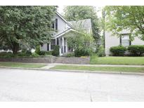 Charming home featuring mature trees, a well-manicured lawn, and a welcoming front porch at 633 N East St, Greenfield, IN 46140