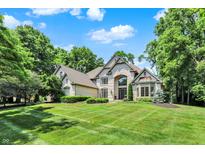 Beautiful stone-clad home with a manicured lawn and mature trees, offering classic elegance and curb appeal at 9690 Irishmans Run Ln, Zionsville, IN 46077