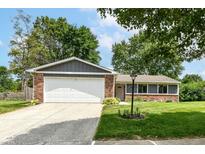 Charming brick home with a two-car garage, green lawn, and mature trees at 12020 Colbarn Dr, Fishers, IN 46038