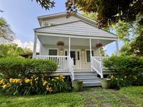 Charming home featuring a welcoming front porch adorned with hanging flower baskets and lush landscaping at 1738 E 71St St, Indianapolis, IN 46220