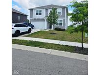 Charming two-story home with a well-manicured lawn, attached garage, and lush, green trees at 1932 Downey Ln, Greenfield, IN 46140