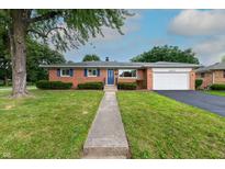 Charming brick ranch home with a well-manicured lawn and a two-car attached garage at 5803 Schoolwood Dr, Speedway, IN 46224