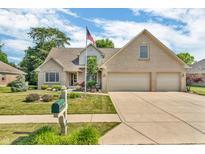 Charming two-story brick home featuring a well-manicured lawn, mature trees, and a three-car garage at 6686 Woodcrest Dr, Avon, IN 46123