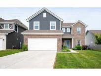Two-story home showcasing a blue-and-brick exterior, a two-car garage, and a well-manicured front lawn at 77 Winding Brook Way, Pendleton, IN 46064