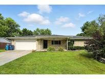 Charming stone ranch home with a well-manicured lawn, mature trees, and an attached one car garage at 8219 Bishops Ln, Indianapolis, IN 46217