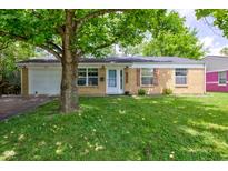 Charming brick home with a well-maintained lawn and mature tree providing shade at 8540 E 37Th Pl, Indianapolis, IN 46226
