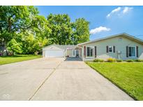 Inviting home showcasing a large driveway, attached two-car garage, and manicured lawn at 901 N Greenbriar Rd, Muncie, IN 47304